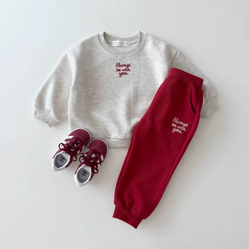 Children's outfit with gray sweatshirt and red pants on a white background