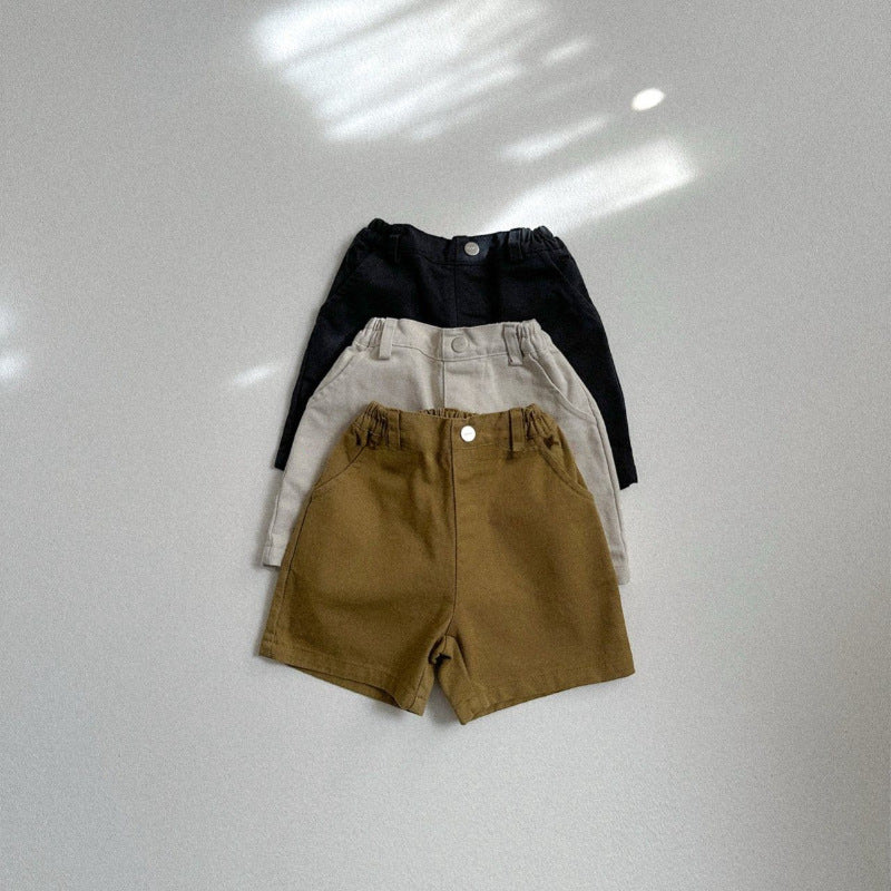 Three pairs of shorts in black, white, and brown on a light gray background