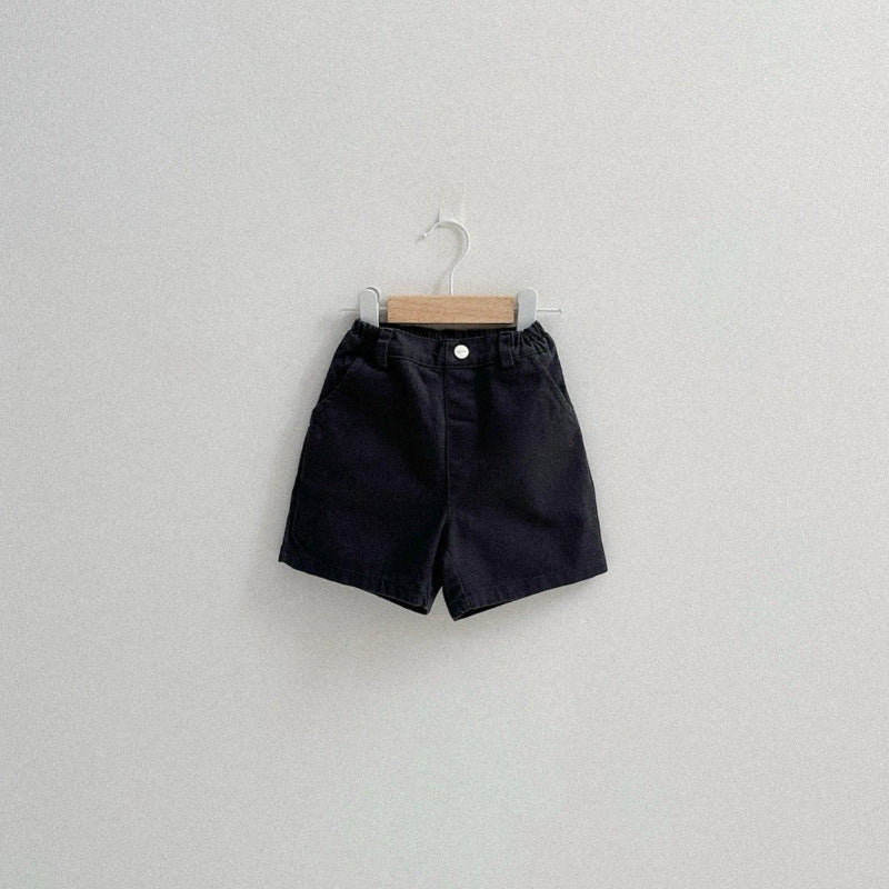 Black shorts on a wooden hanger against a light gray background