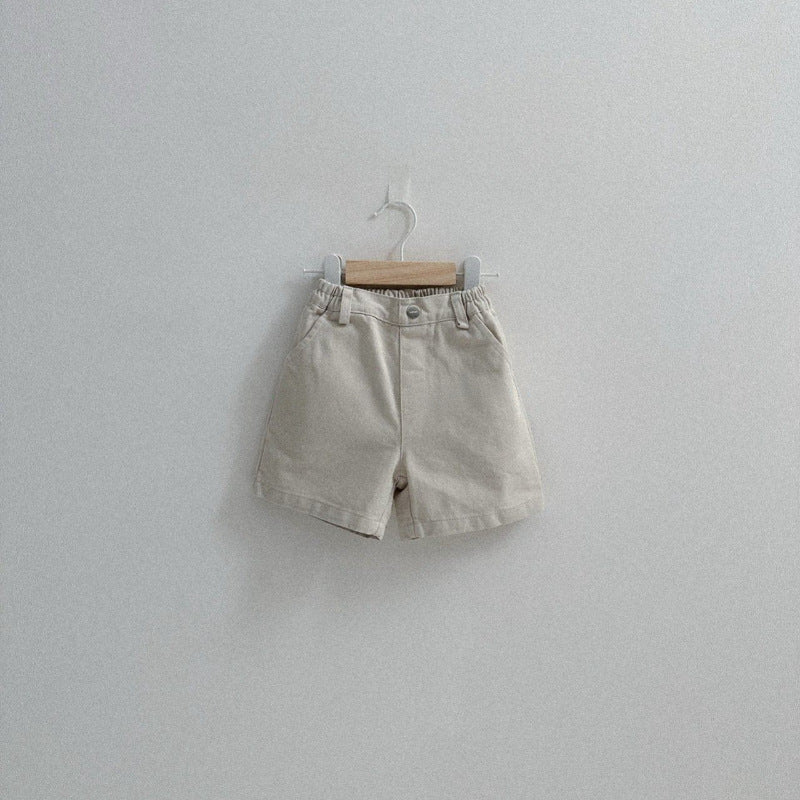 Three pairs of shorts hanging on a white wall.