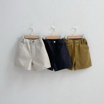 Three pairs of shorts hanging on a white wall.
