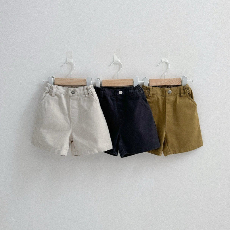 Three pairs of shorts hanging on a white wall.