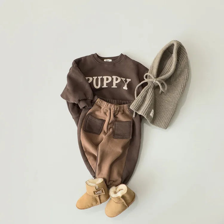 Children's brown outfit with 'PUPPY' sweater, pants, and boots on a light gray background