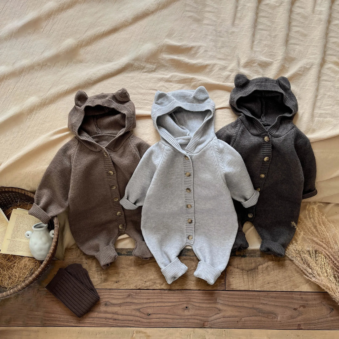 Two baby rompers on a wooden surface with a neutral background