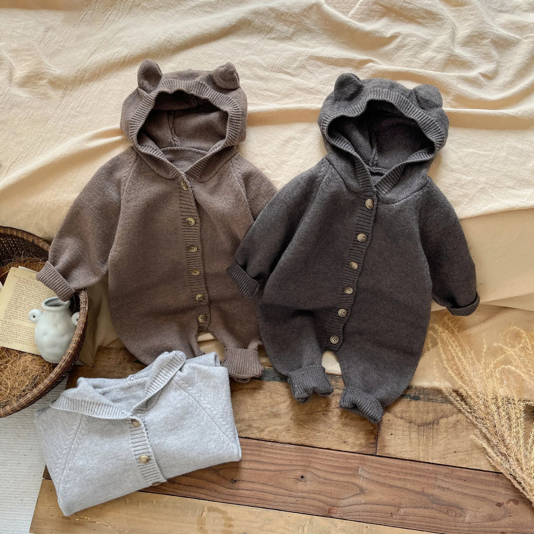 Two baby rompers on a wooden surface with a neutral background