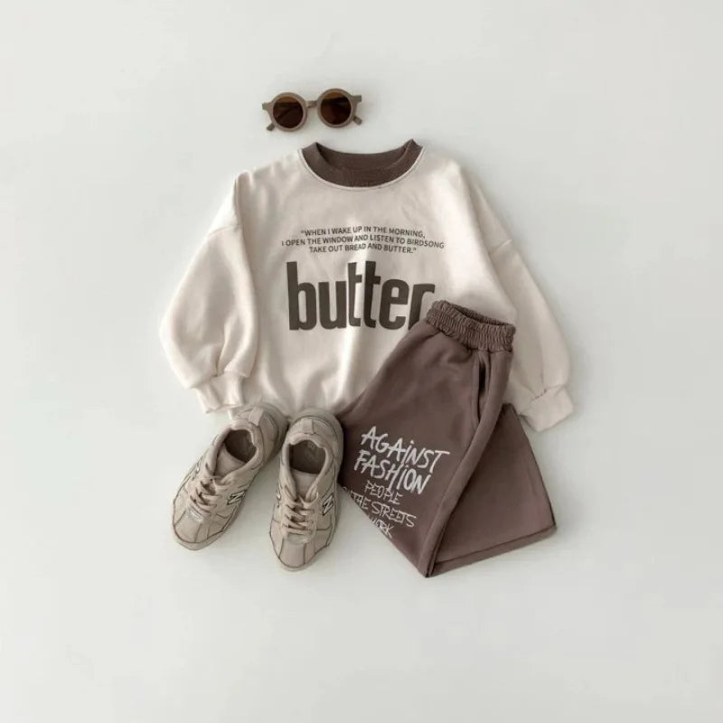 White sweatshirt with text, brown pants, sneakers, and sunglasses on a white background