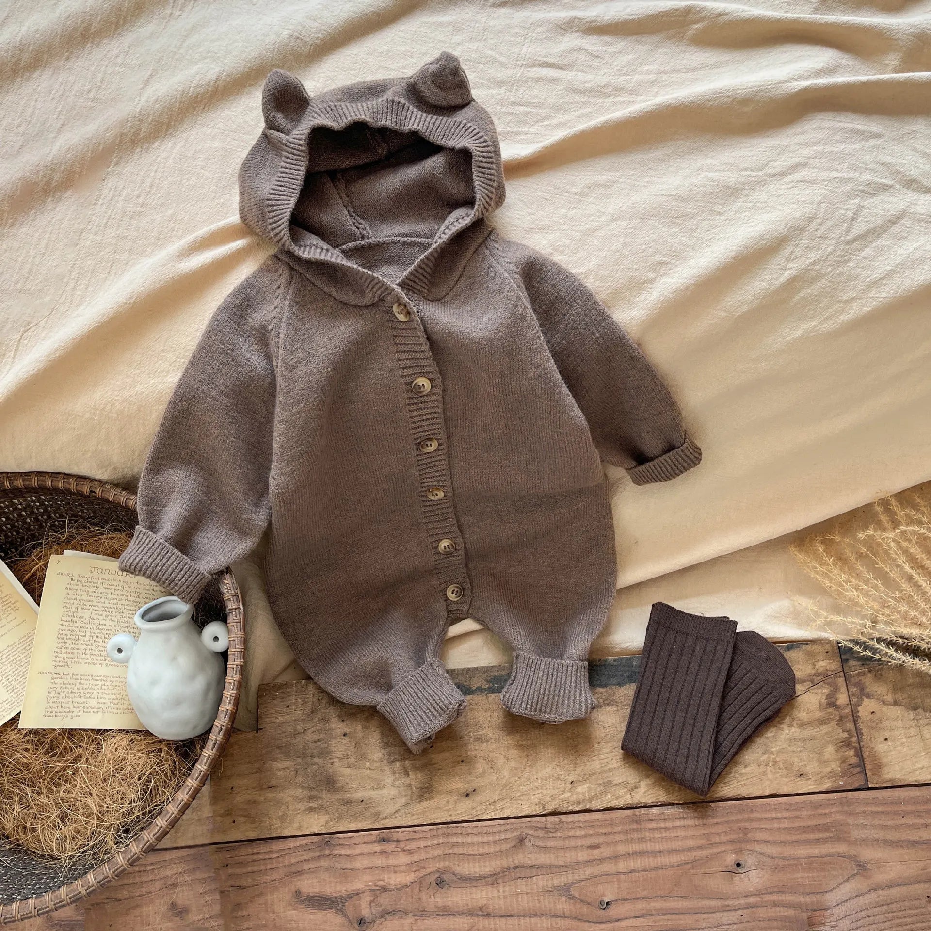 Brown knitted baby outfit with ears on a wooden surface